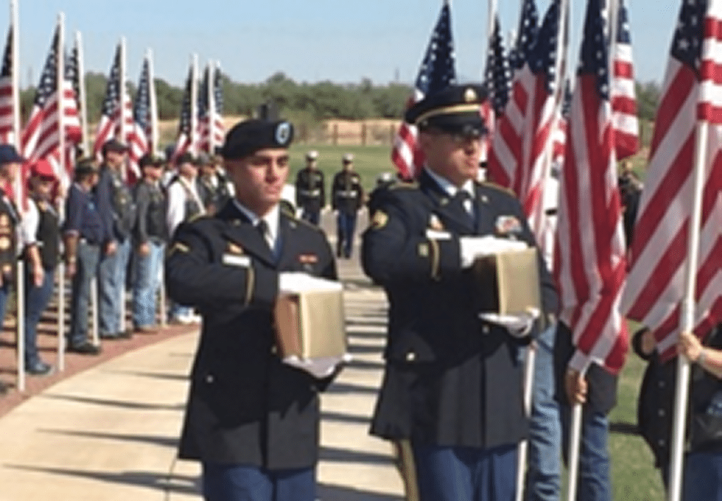 Missing In America procession with members holding United States Flags and soldiers carry cremains.