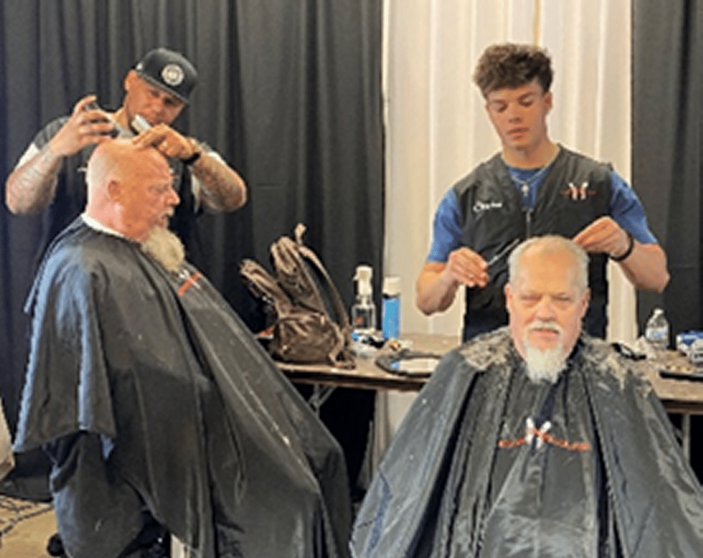 Volunteer Barbers giving haircuts to veterans at Stand Down event.