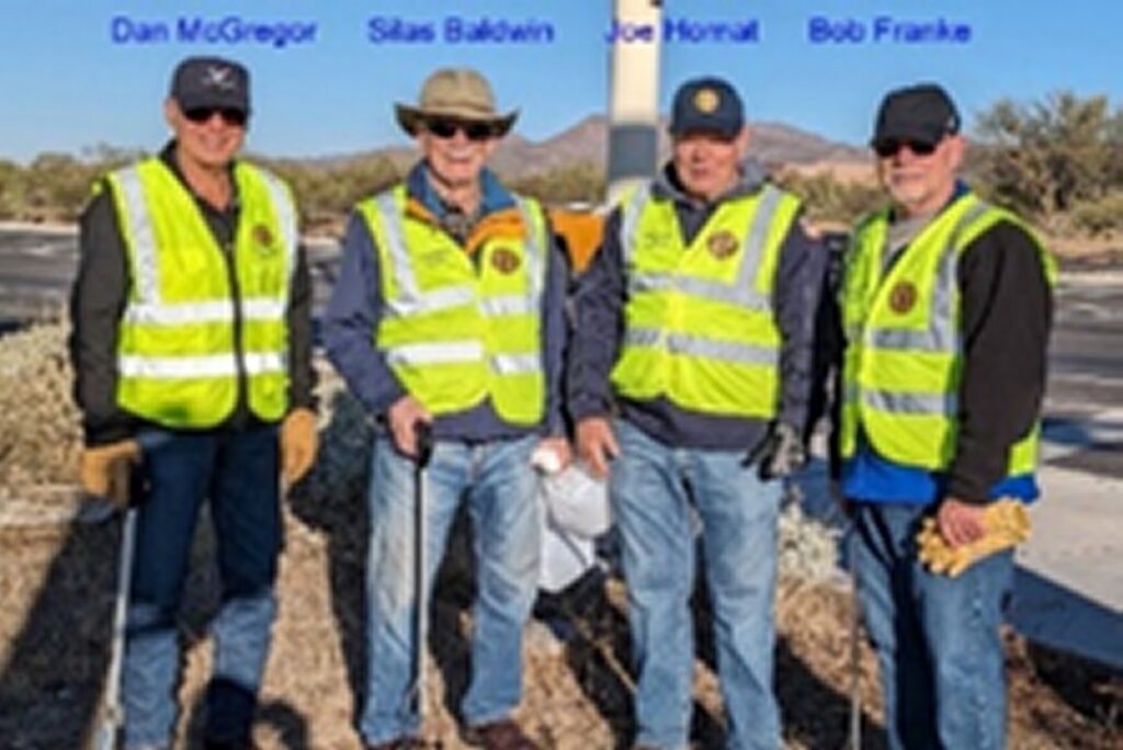 Four members of Post 132 road cleanup crew in fluorescent yellow vests.