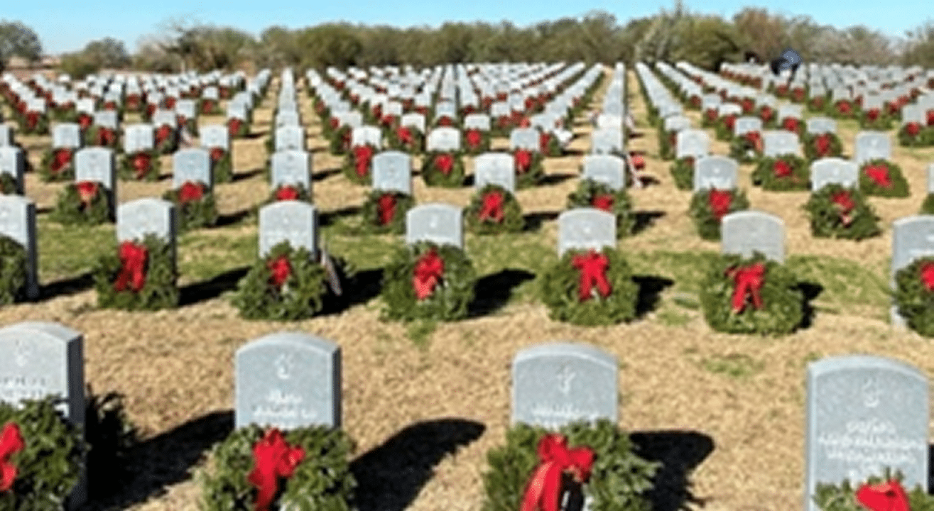 View of headstones in a cemetery with Wreaths placed on headstones.