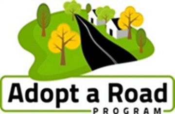 Adopt A Road sign with black road in center and green grass borders.