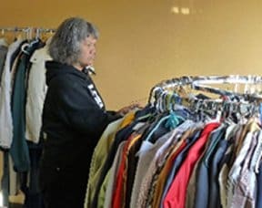 Stand Down Female Volunteer placing and sorting clothing on racks.