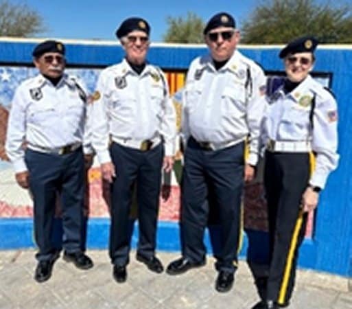 Four members of Post 132 Color Guard team with blue beret, pants and white shirts.