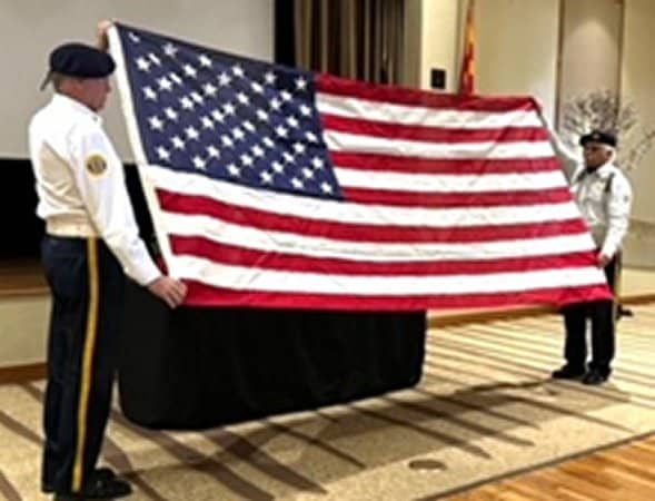 Two members of Post 132 Color Guard in uniform presenting the United States Flag.