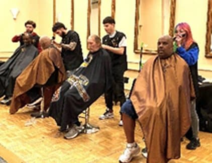 Volunteer barbers from local school giving veterans haircuts at Stand Down event.