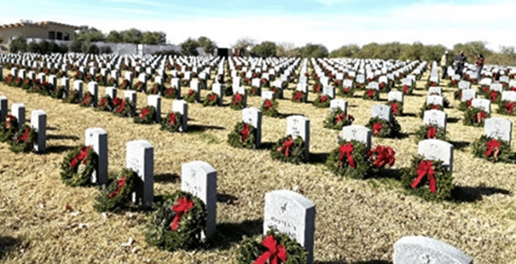 View of hundreds of headstones with wreaths lying against them in Veterans graveyard.