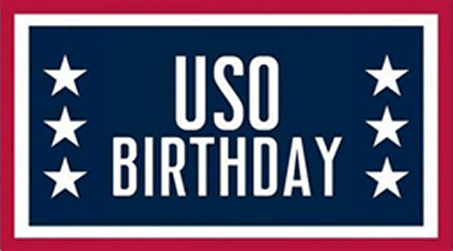 Rectangular sign with red border and white inner border surrounding blue field with three white five point stars on each side of blue field and USO Birthday in white letters centered.