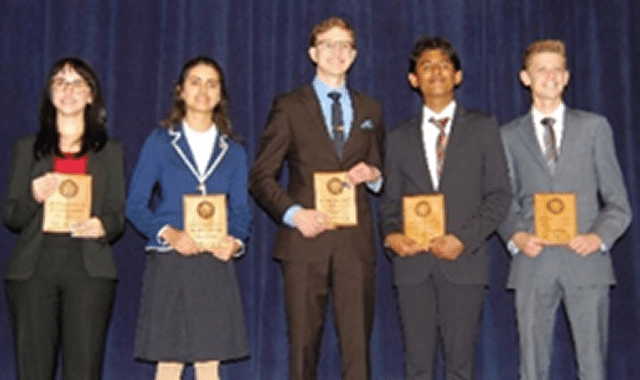 Portrait of two young ladies and three young men holding award plaques, all past winners from an American Legion sponsored Oratorical competition.