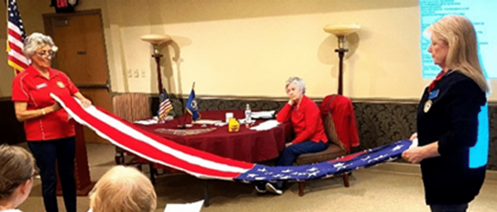 Two female members of Auxiliary Unit 132 demonstrating United States flag folding procedure for other members.